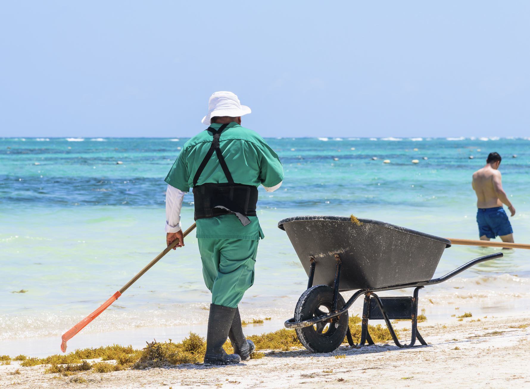 Trabajador mexicano barriendo Sargassum