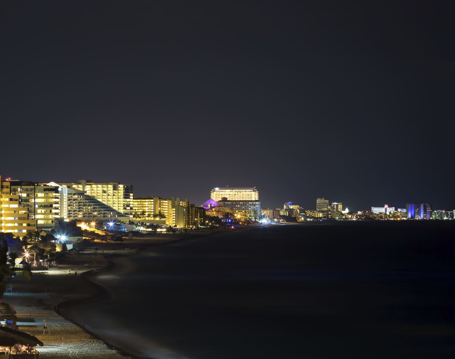 Luces de la zona hotelera de Cancún brillan desde los hoteles durante la noche