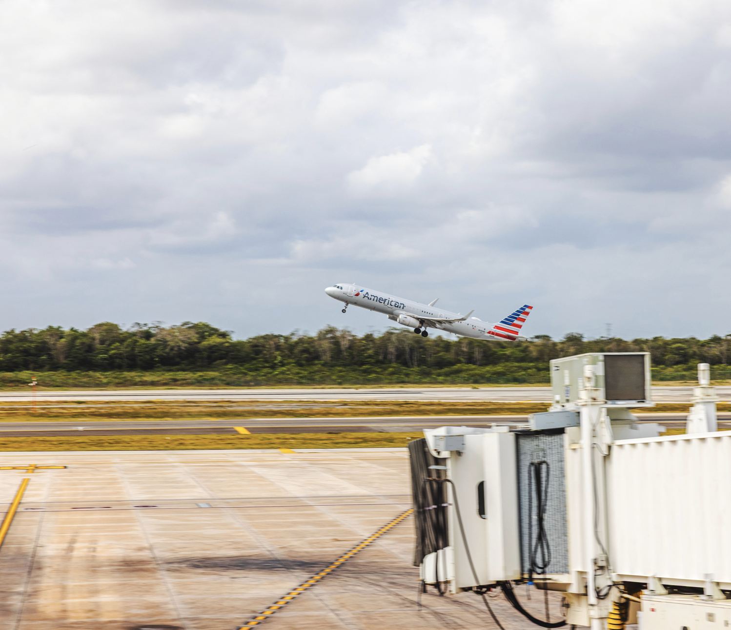 Aviones de American Airlines despegando en el aeropuerto de Cancún contra el cielo azul con nubes blancas. Cancún. México