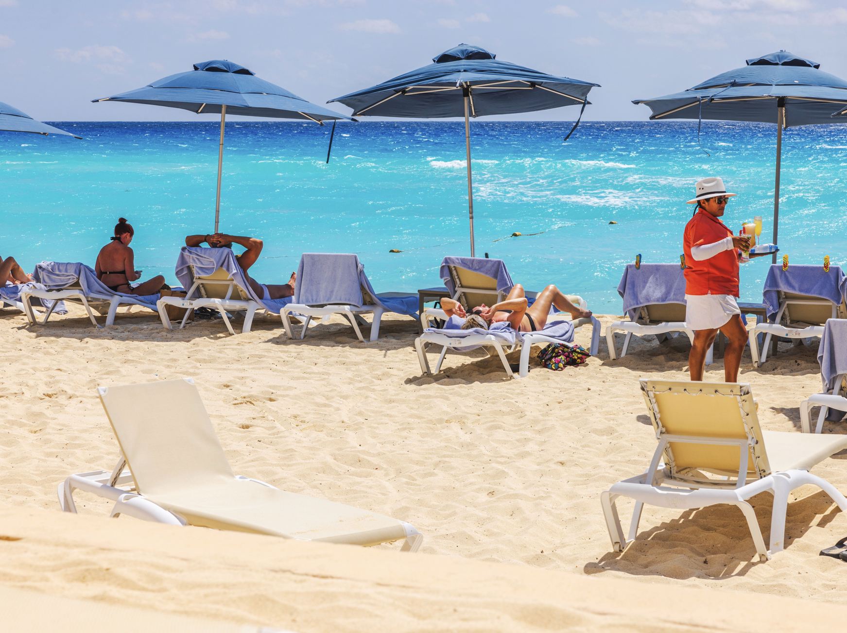 El trabajador de empleados lleva a Drinsk al turista en la playa en Cancún