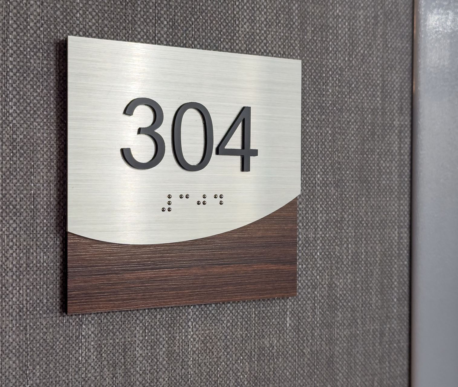 Fotos de una habitación de hotel marrón y plateada número 304 con braille