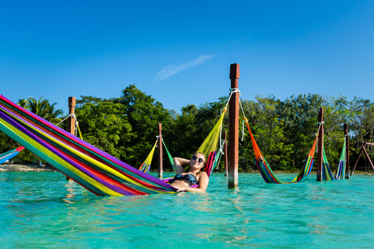 Turista femenina descansando en una hamaca en la laguna de Bacalar en Bacalar, México