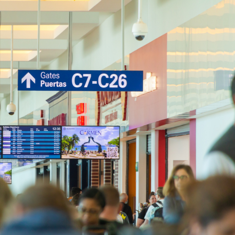 Turistas caminando por el Aeropuerto Internacional de Cancún para llegar a las puertas de embarque
