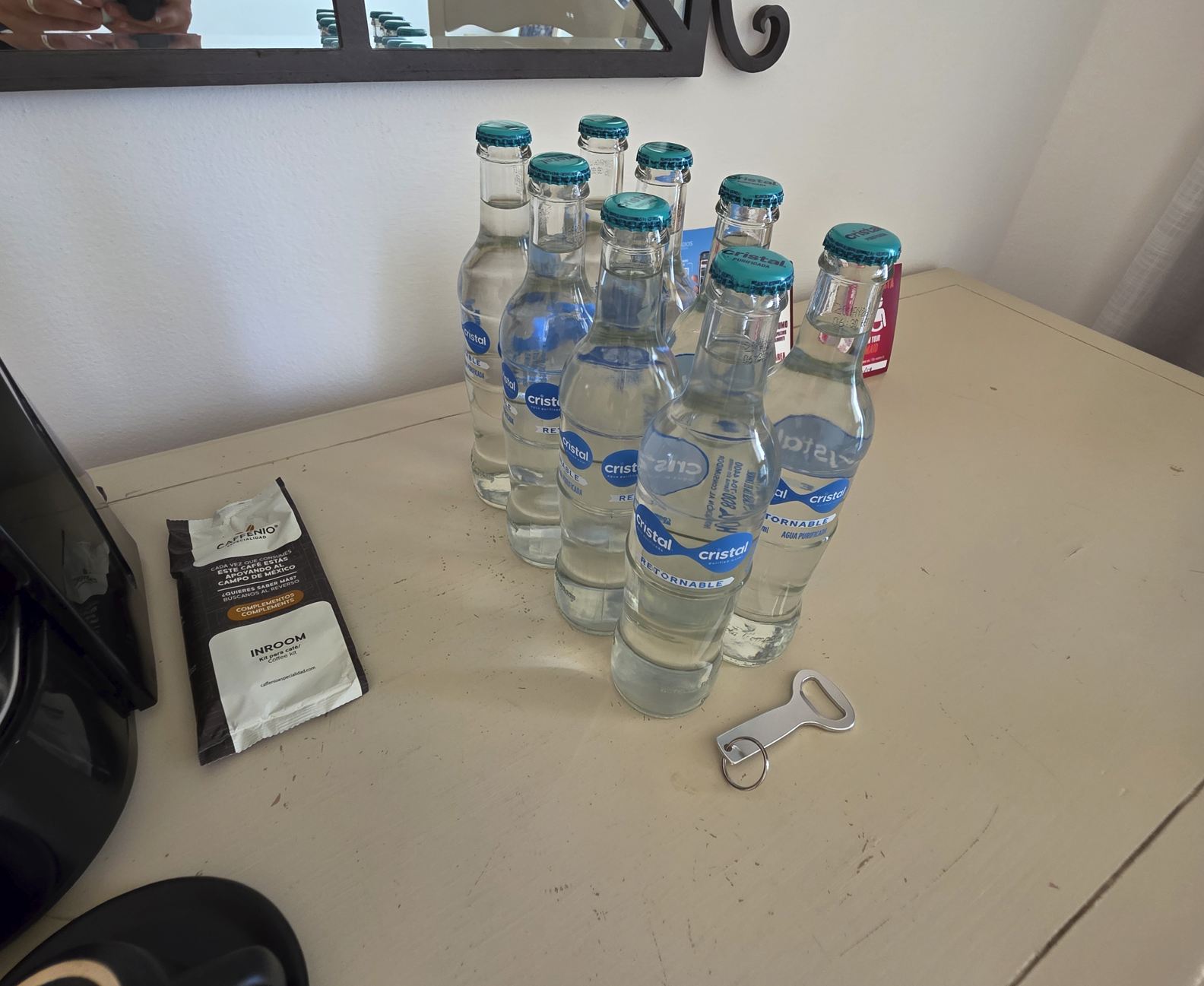 Botellas de agua adicionales en la habitación del hotel Sandos Cancún Resort Abrebotellas sobre la mesa. Foto original de Trevor Kucheran