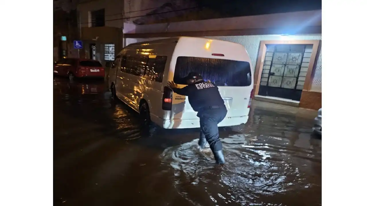 Aquí se ve a un oficial de la policía estatal empujando una camioneta a través de un área inundada el 29 de mayo de 2026.