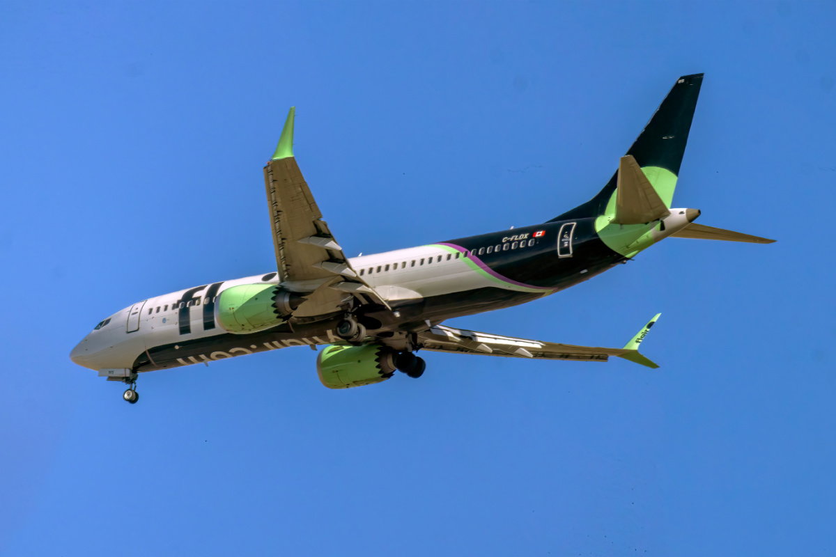 Calgary, Alberta, Canadá. 22 de octubre de 2025. Un vibrante avión Boeing 737 MAX de Flair Airlines, con su distintiva librea verde y negra, se eleva a través de un cielo azul claro, simbolizando los viajes con descuento modernos.