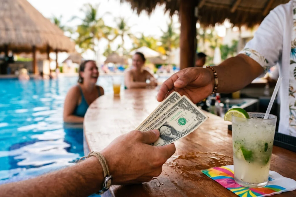 Hombre entregando billetes de un dólar a un camarero en Cancún