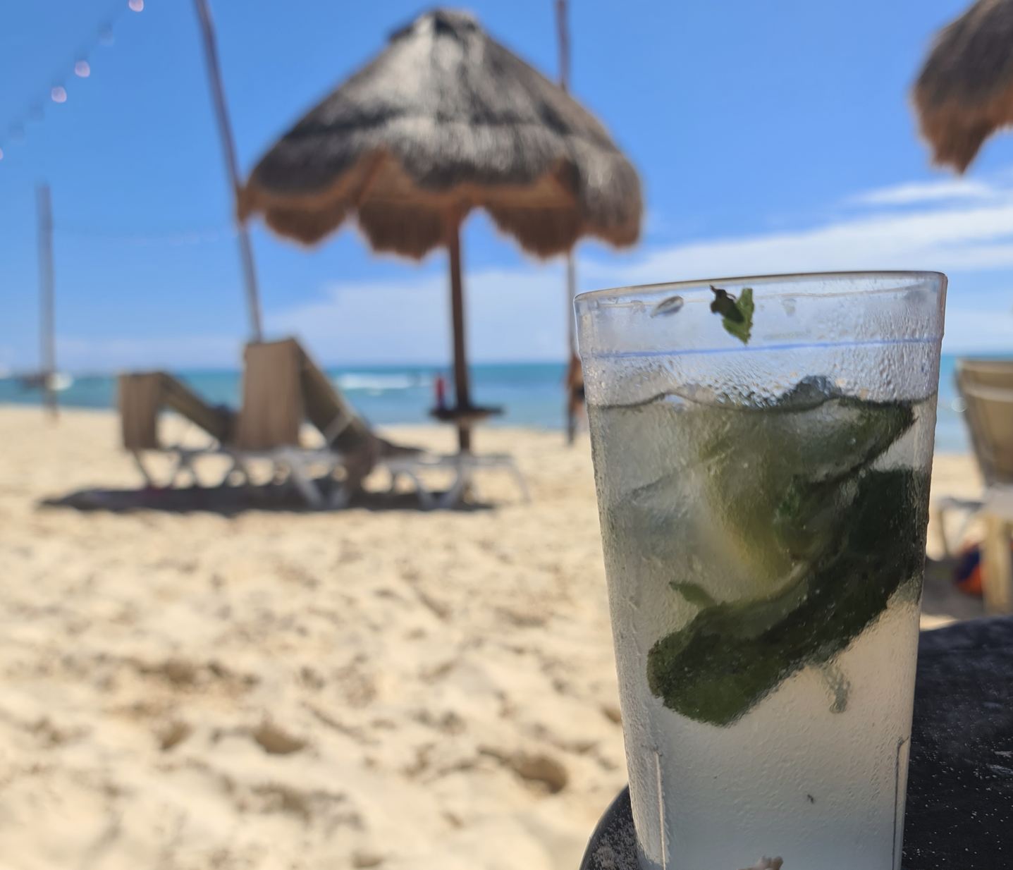 Mojito en vaso de plástico sobre la arena.