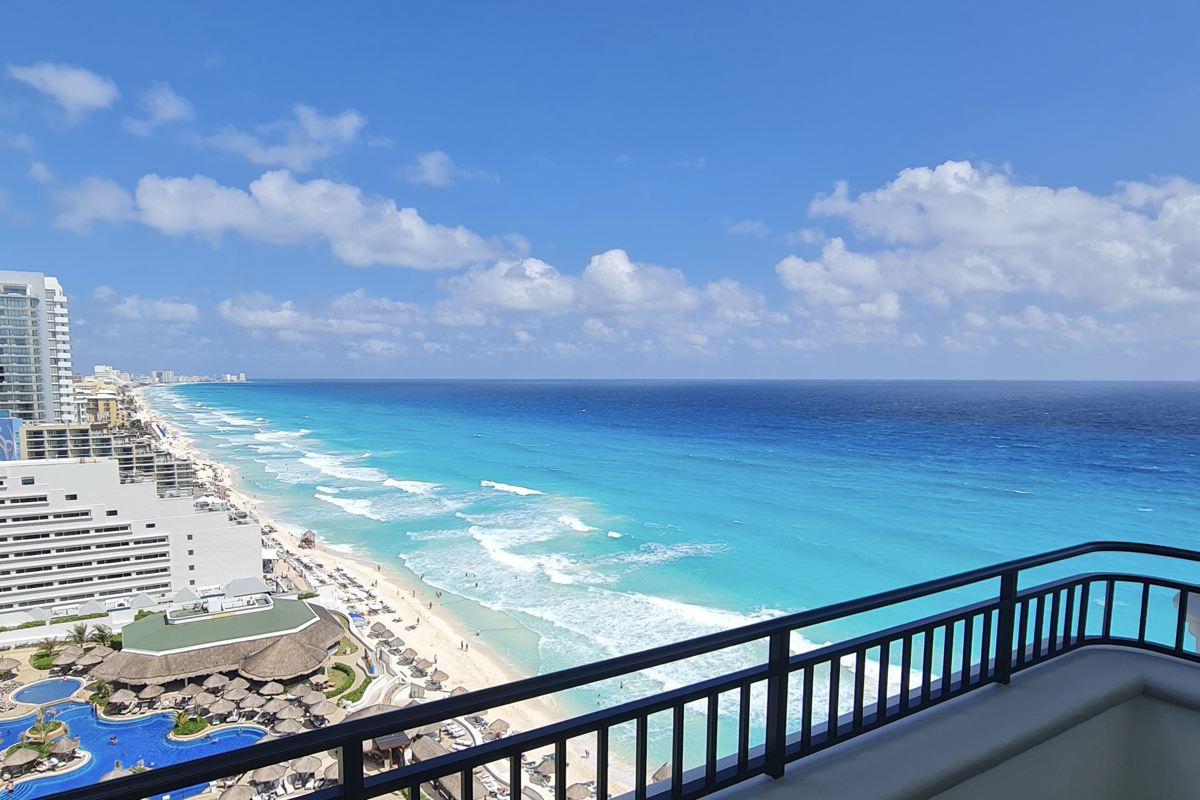 Vista desde el balcón del JW Marriott con vista a la playa de arena blanca y agua azul agua en Cancún. Foto original de Trevor Kucheran.