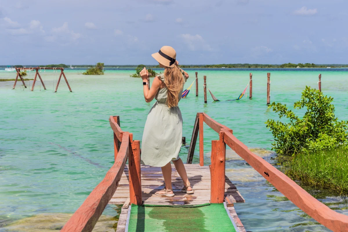 Madre con su hijo pequeño explorando el muelle de madera sobre las aguas turquesas del lago Bacalar, México. Concepto de destino de viaje tropical pacífico